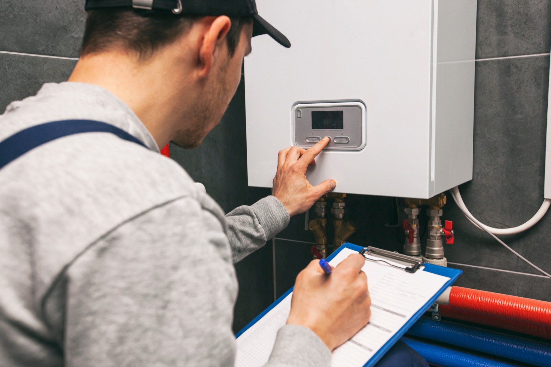 Engineer adjusting a boiler with a clipboard