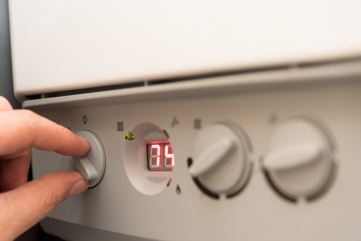 Fingers of an adult man turning on a British combi gas boiler